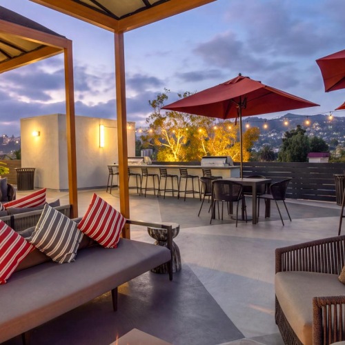 a patio with a fire pit and chairs and umbrellas